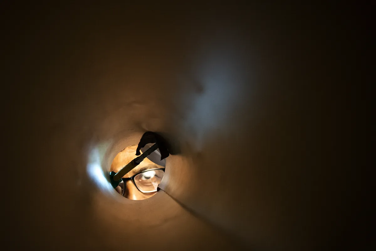 Rohrinspektion – Blick durch das Kanalrohr in Erding Blick durch ein Rohr auf einen Techniker mit Stirnlampe – Einsatz in Erding